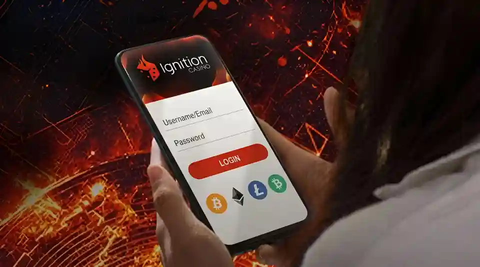 Hand holding a phone showing the Ignition Casino login screen with username, password, and cryptocurrency deposit icons